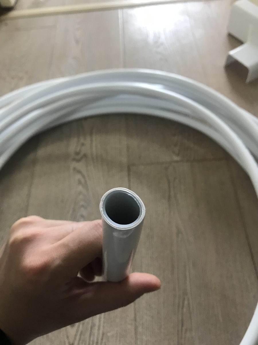 手持截断的灰色采暖管材与地面成卷盘管