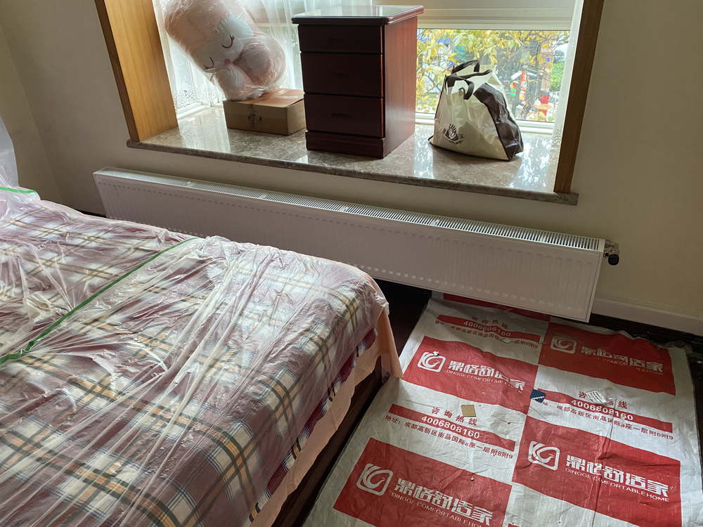 卧室窗台下贴地安装的白色板式散热器
